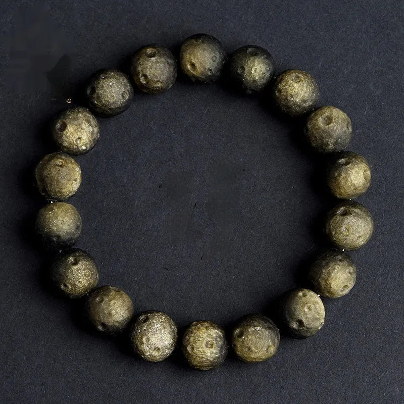 Close-up of a natural obsidian crater ball bracelet with grinding-treated beads on a wrist.