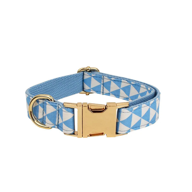 Blue cloth dog vest, matching collar with triangular ring, rope leash, and decorative bow laid out as a four-piece set.