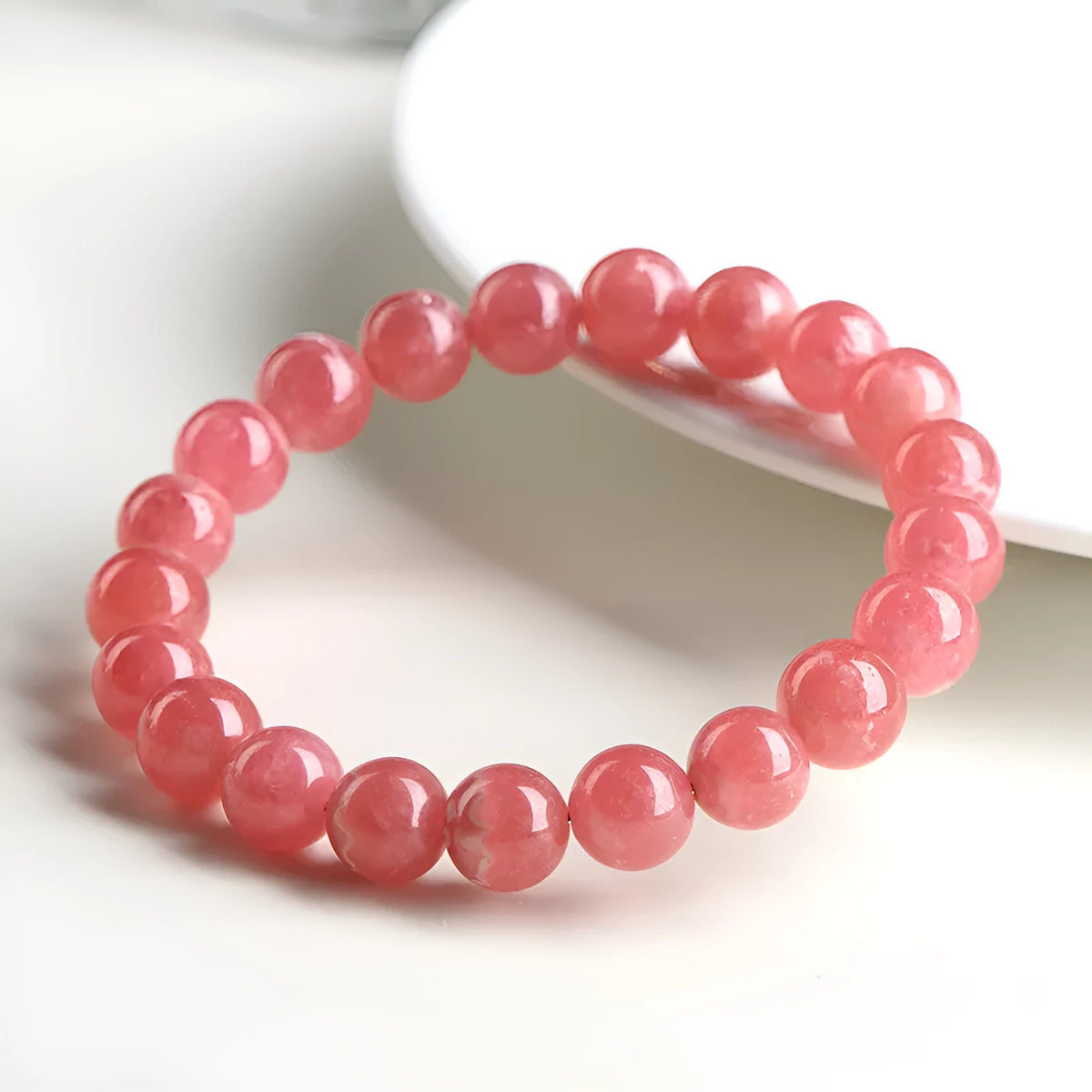 Women's red rhodochrosite crystal bracelet with geometric beads and a Longevity Lock charm.