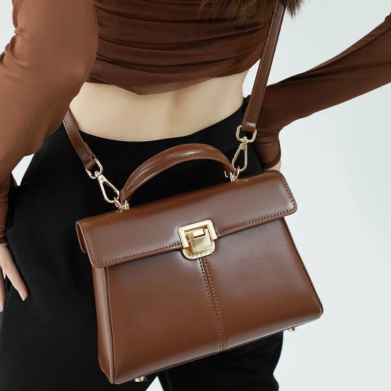 Women's black leather shoulder bag with vachette clasp showing horizontal square shape and shoulder strap