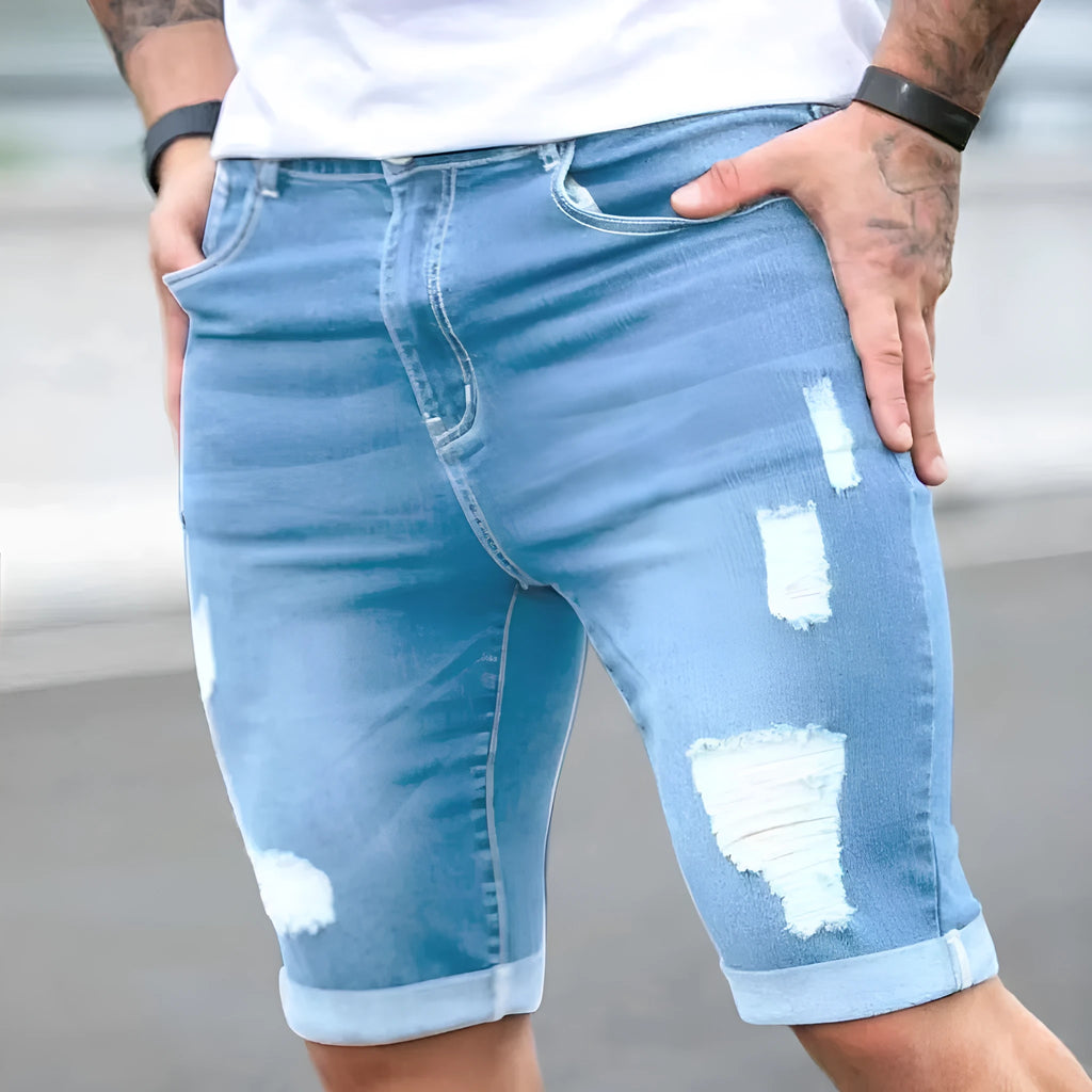 Sky blue men's denim shorts with manual distressing holes on the legs, showing a low waist and zip fly.