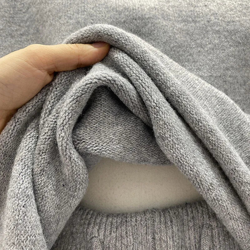 Woman wearing a loose grey long sleeve sweater and matching wide leg knit shorts lounge set.