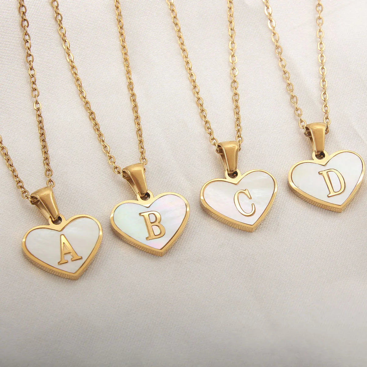 Heart-shaped letter necklace with white shell detail on gold-plated stainless steel chain