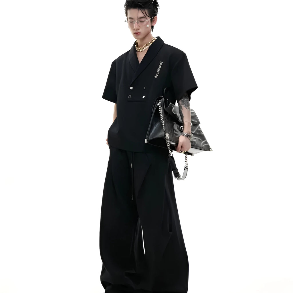 Men's dark grey V-neck cotton sports jacket with padded shoulders and metal detail, worn with matching shorts