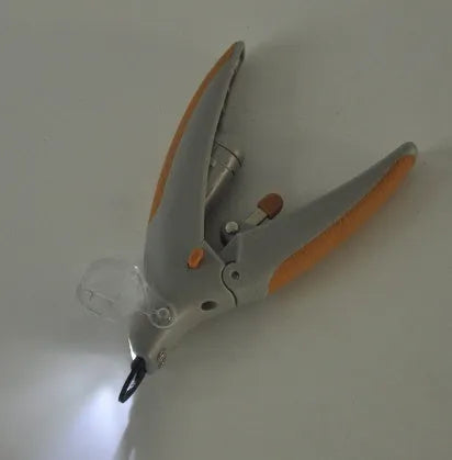 ABS plastic dog nail clipper with light on and imitation blood line guide visible on cutting head.