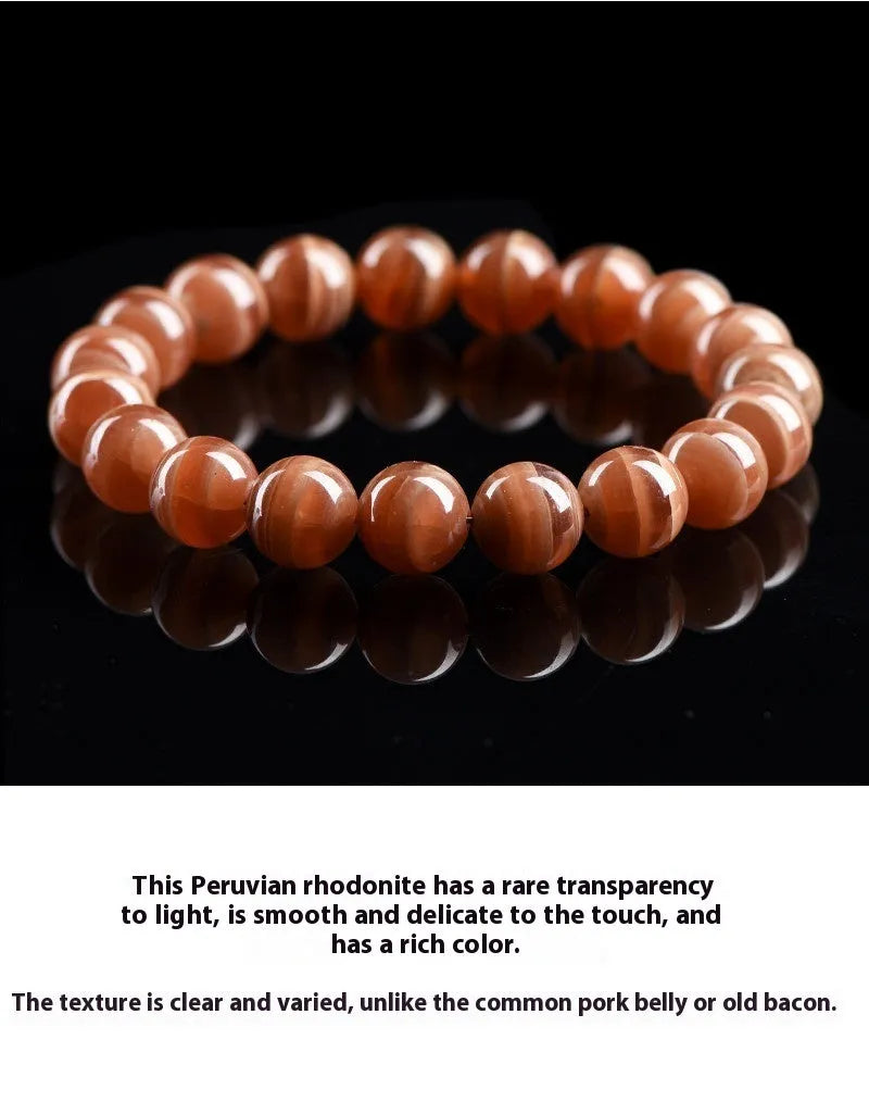 Natural old mine rhodochrosite round bead bracelet with ruyi design on a wrist.