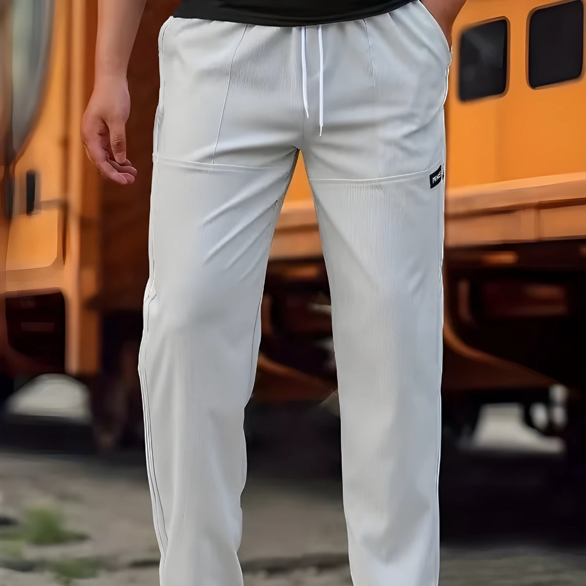 Men's light grey tapered slim-fit trousers with an elastic waistband on a hanger.