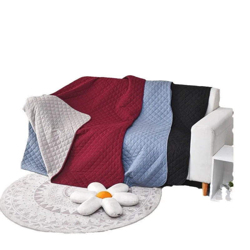 Reversible waterproof dog blanket on sofa showing two colour options, protecting furniture from pet accidents
