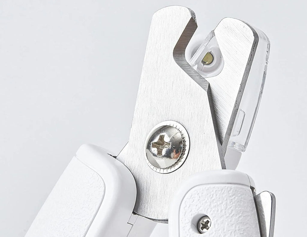White pet nail clippers with LED light, transparent anti-splash guard, and integrated nail file on a grey background.