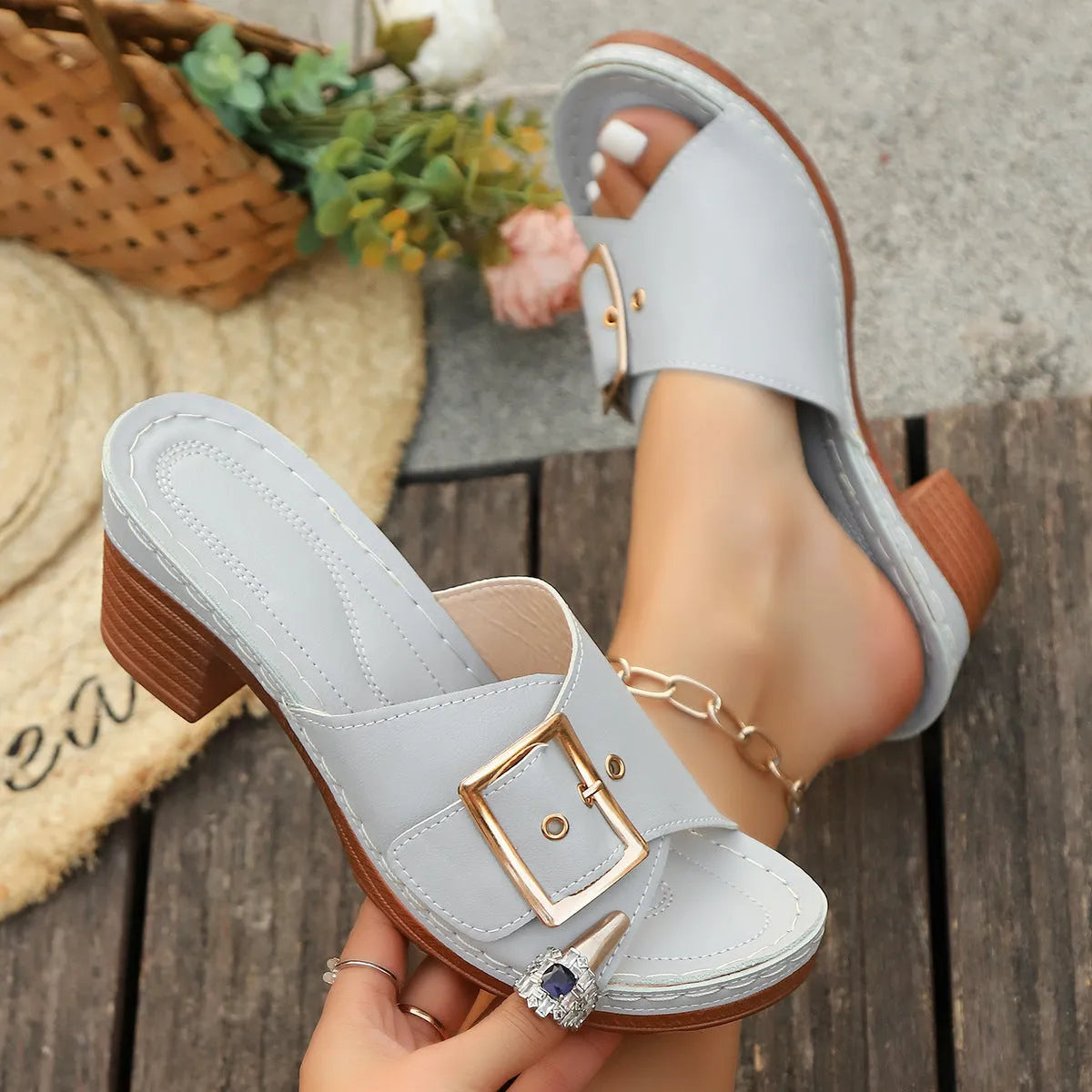 Women's black slippers with a chunky heel, metal buckle strap, and round toe on a rubber sole.