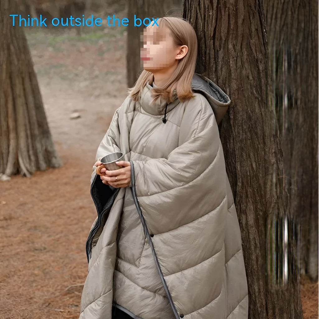 Adult wearing a gray hooded outdoor cloak that converts into a sleeping bag, shown laid flat at 200cm x 140cm.