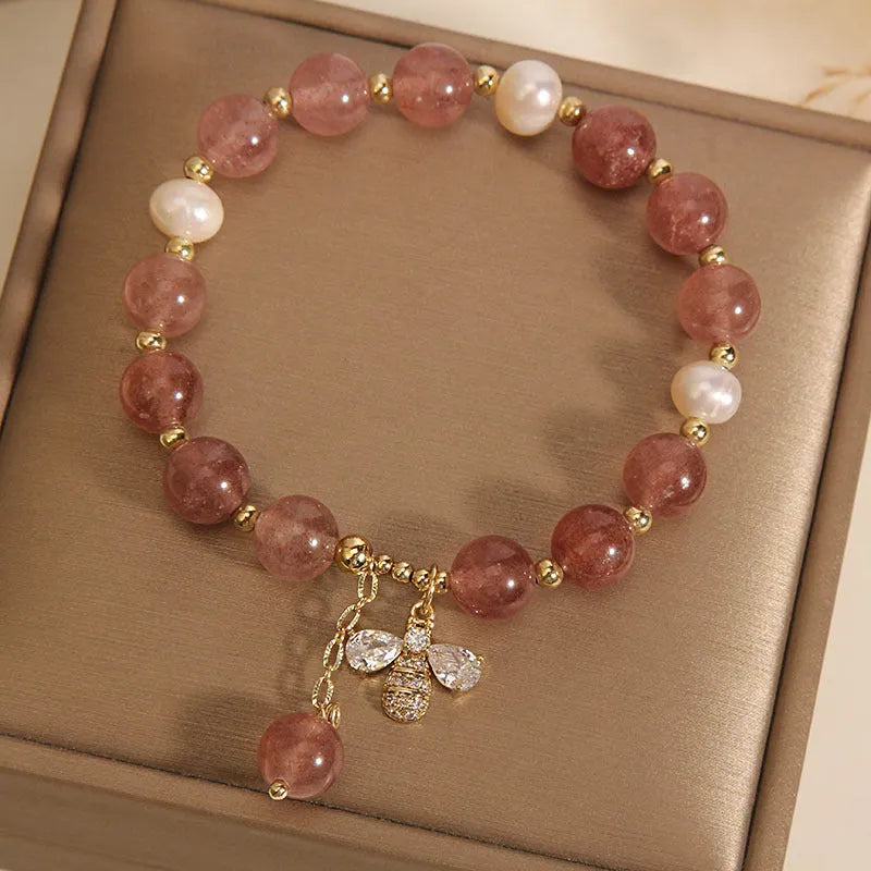 Women's pink strawberry quartz and white freshwater pearl bracelet with zircon accents on wrist