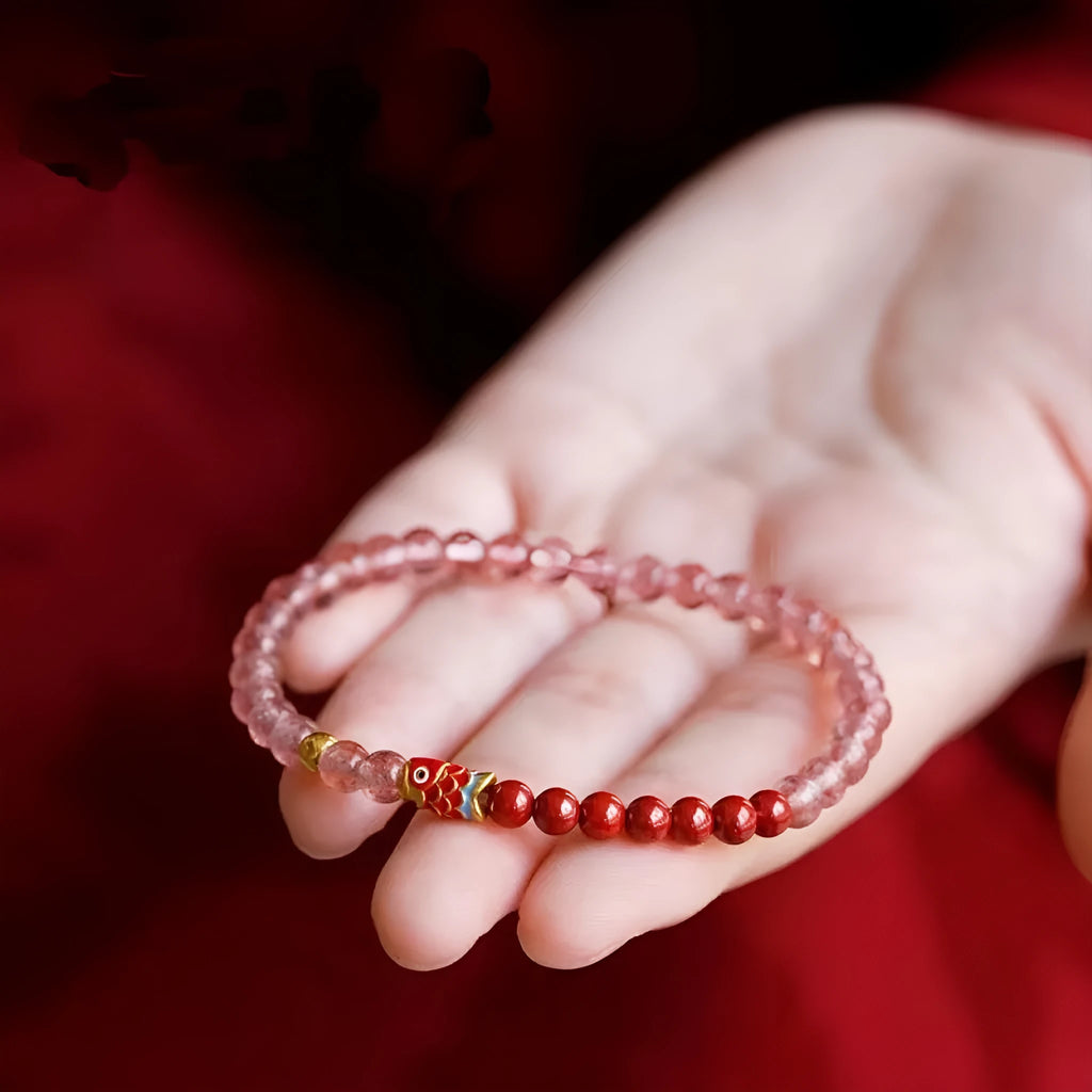 Women's bracelet with purple cinnabar and pink strawberry quartz beads, koi design, on wrist.