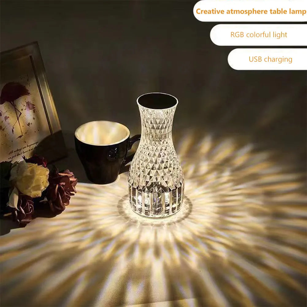 Transparent crystal vase shaped LED table lamp with remote control on a wooden bedside table.