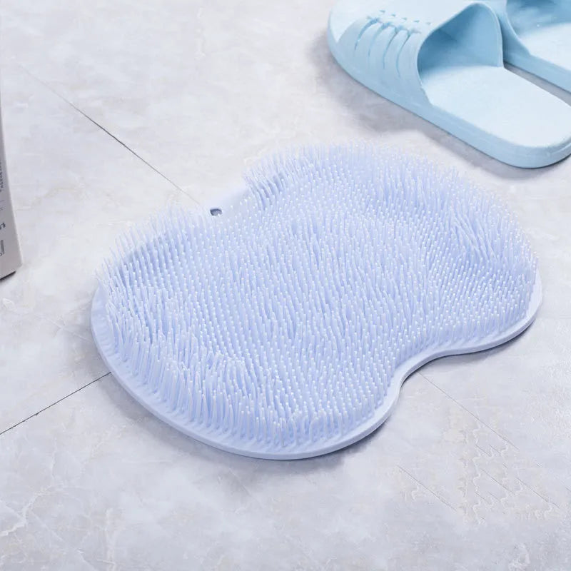 Orange silicone bristle bath brush with suction cup base on a bathroom floor