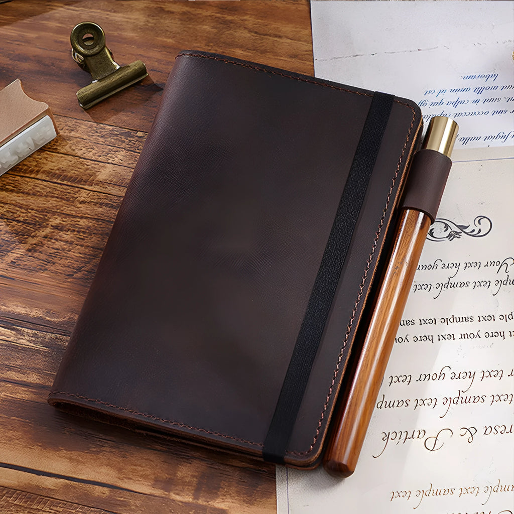 Handmade notebook with cowhide cover open on a table, showing 100 gsm wood-free paper inside