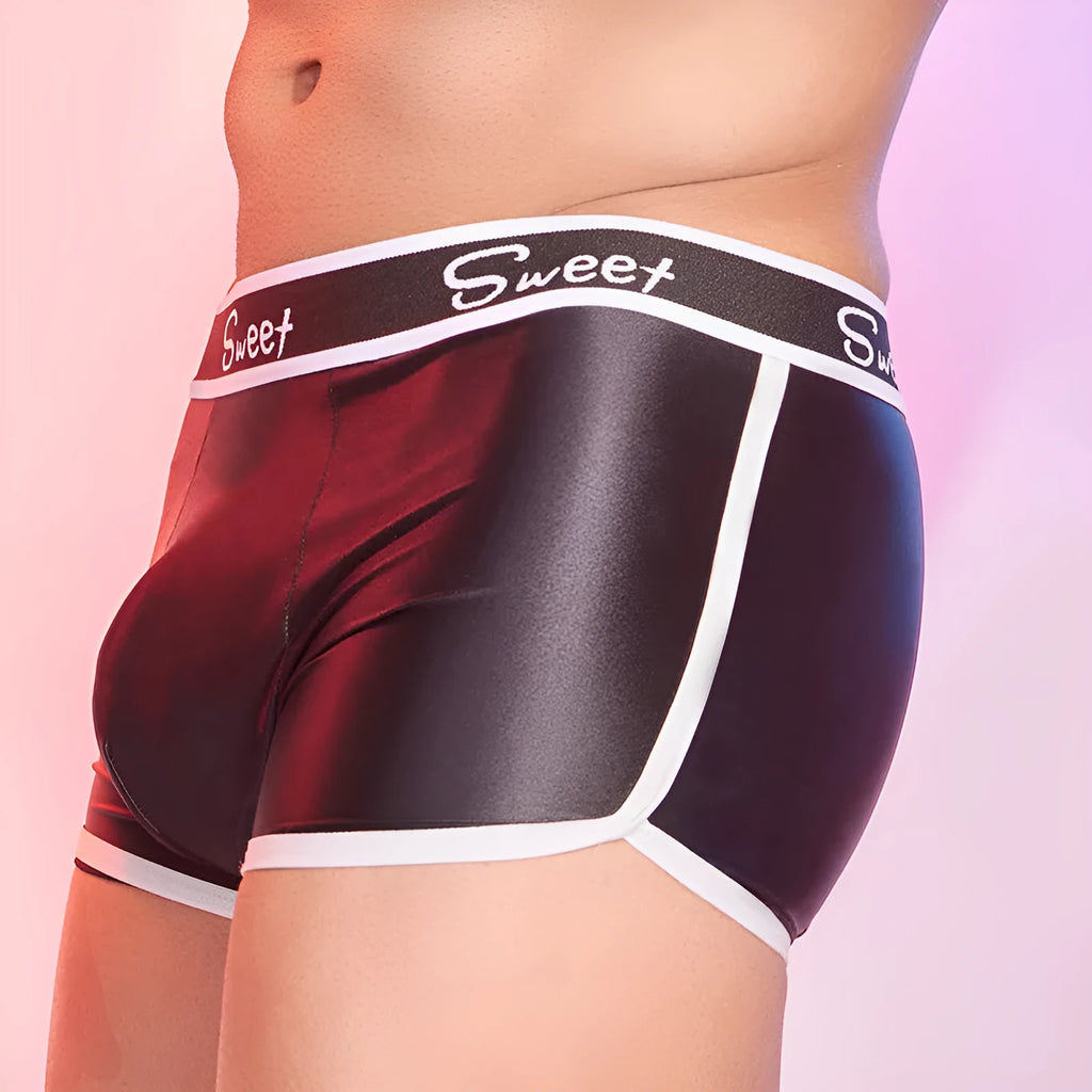 Man's silky shiny boxer shorts in black, white, and sapphire blue colours laid flat.