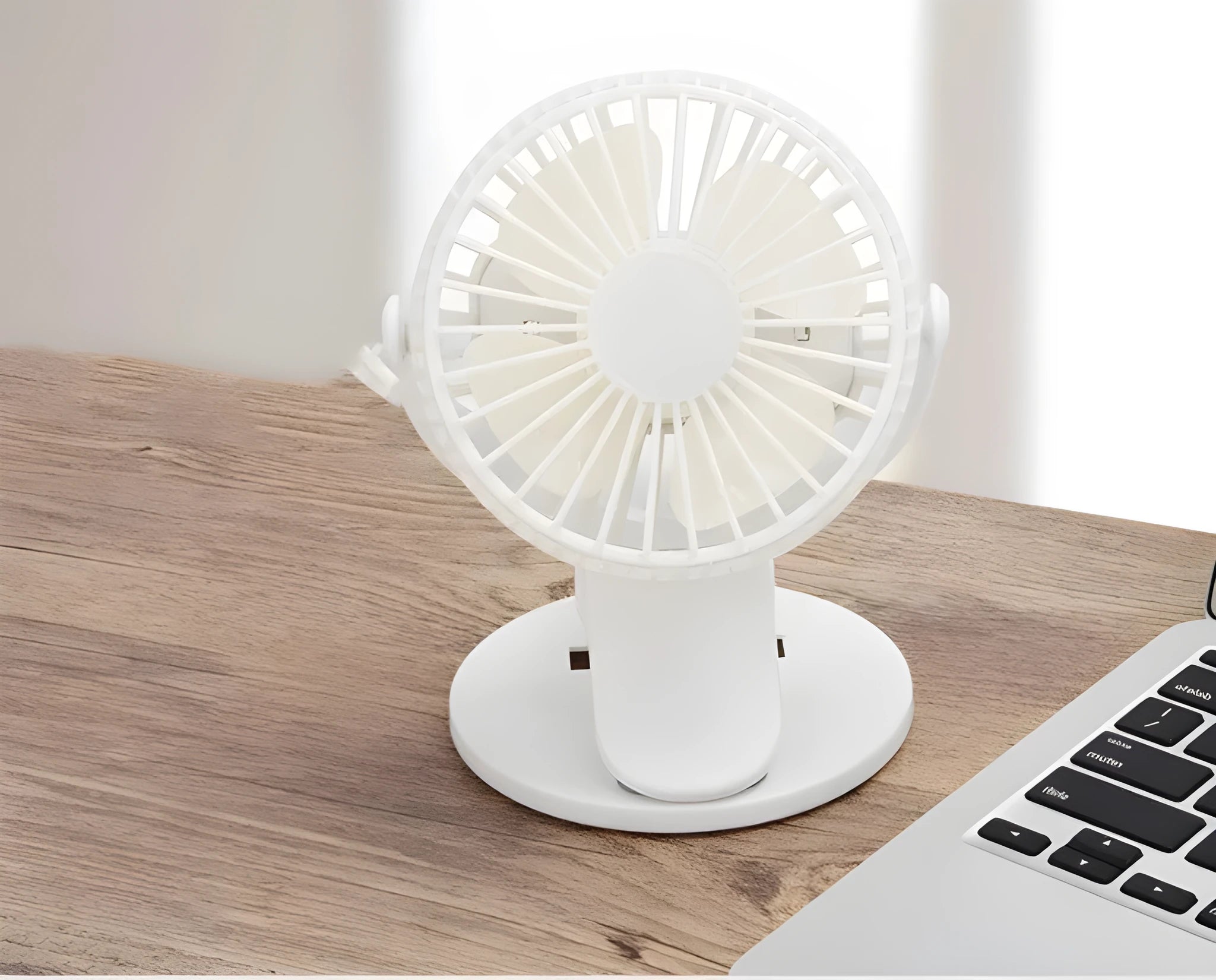 Mini clip fan with USB charging port mounted on desk edge showing plastic blades and piano button controls