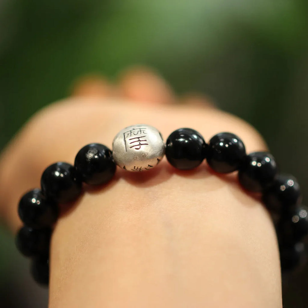 Handmade women's black agate bracelet with 10mm beads and a sterling silver clasp on a wrist.