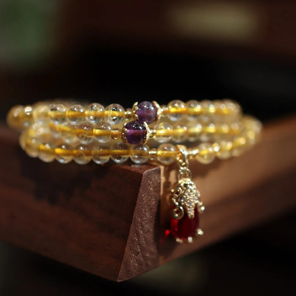 Handmade bracelet with Brazilian rutilated quartz beads, three gold circles, and a hanging bead pendant.