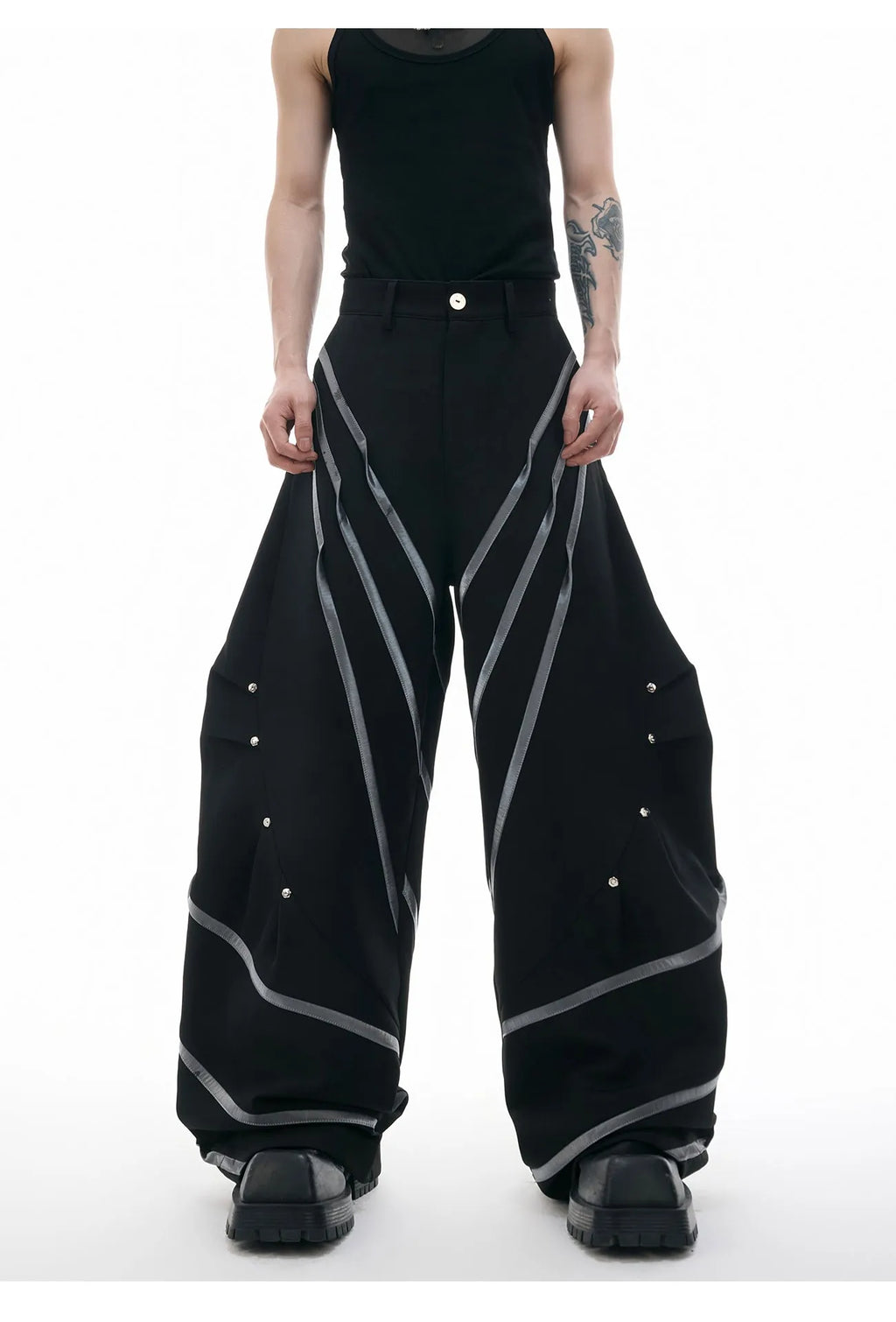 Men's black polyester trousers with metal striped rivets and pleated detail on a white background.