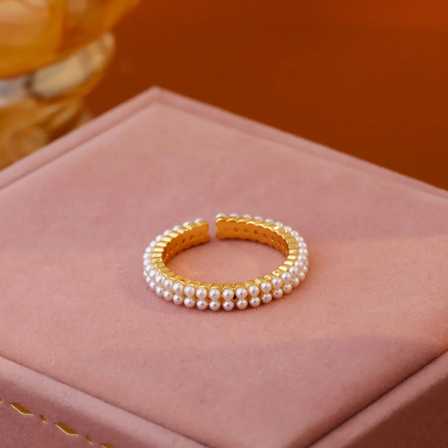 Gold geometric open ring with pearl detail on a model's finger.