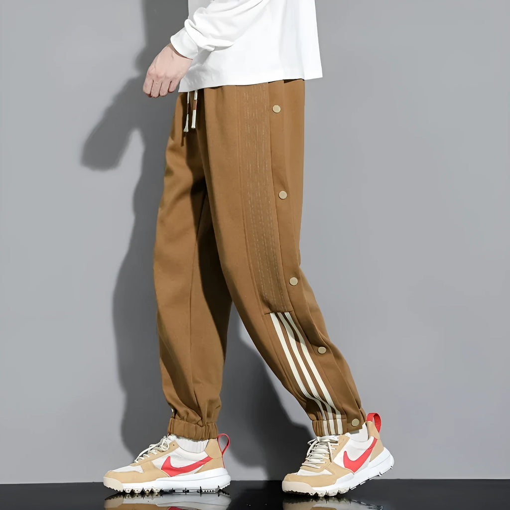Man wearing black high-waisted, loose, ankle-tied sweatpants with a belt, showing the drawstring waist.
