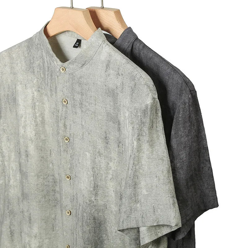 Man wearing a loose-fit black grey linen cardigan-style shirt with a stand collar and short sleeves.