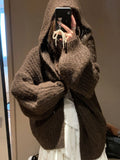 A woman wearing a thick, loose-fit hooded cardigan sweater in a milky white colour.