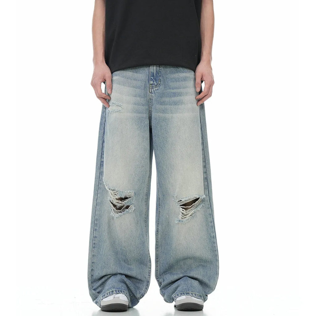 Man wearing blue retro-style straight-leg jeans with a ripped, distressed finish on the legs.