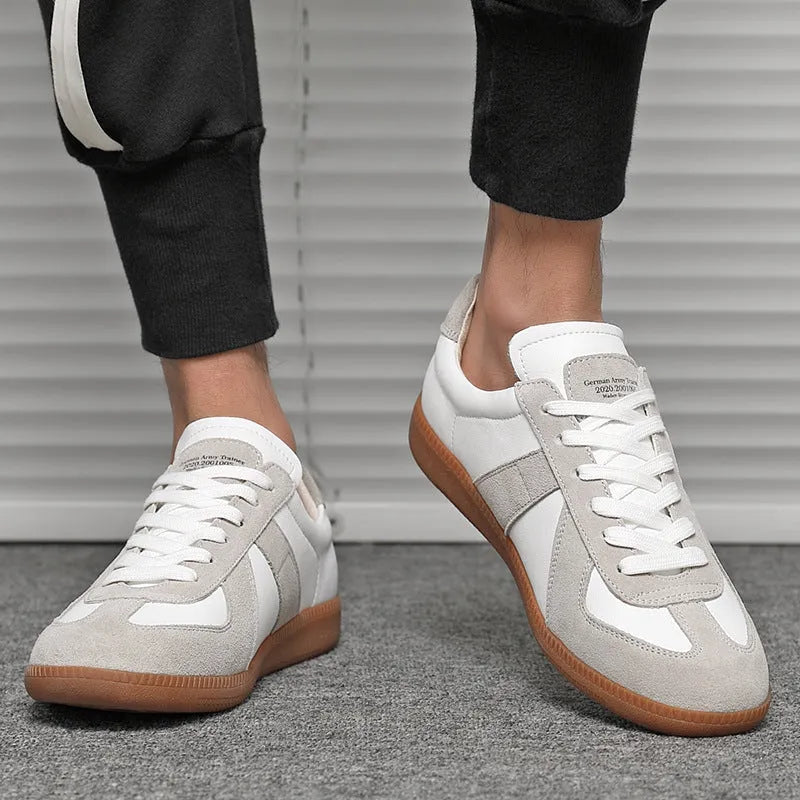 White low-top retro unisex sneakers with round toe and lace-up front on a plain background.