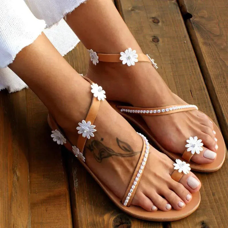 Brown women's flat sandals with decorative flowers and a herringbone toe shape on a rubber sole.
