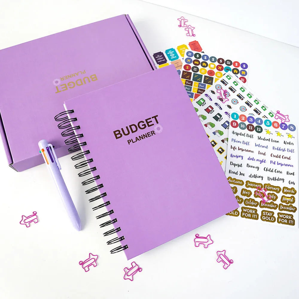 Purple coil-bound financial planning notebook with pen and stickers on a desk.