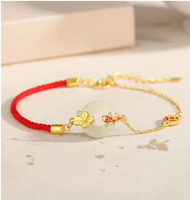 Close-up of a women's retro bracelet with a Hetian Jade stone, red cord, and a gold Koi fish safety buckle on a 925 silver chain.