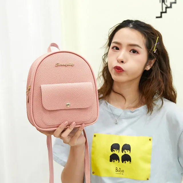 Small black PU leather ladies backpack with zipper, shown on shoulder