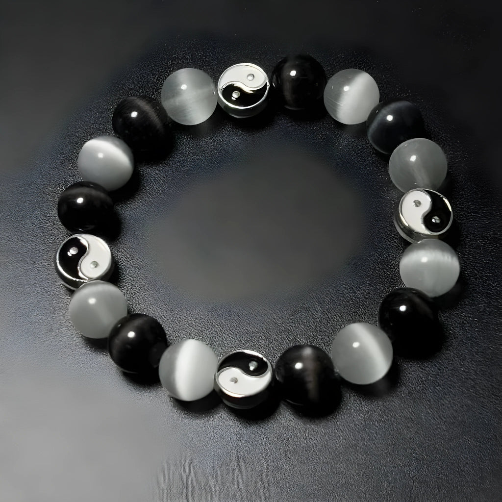Close-up of a polished opal Tai Chi beaded bracelet with black agate ornamentation on a wrist.