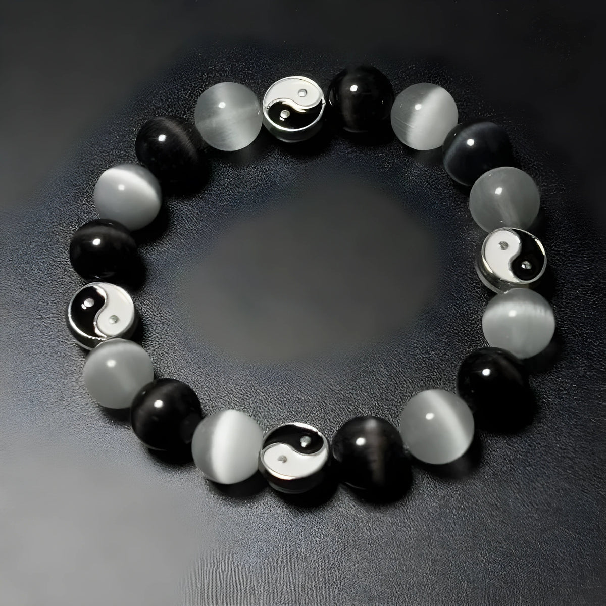 Close-up of a polished opal Tai Chi beaded bracelet with black agate ornamentation on a wrist.