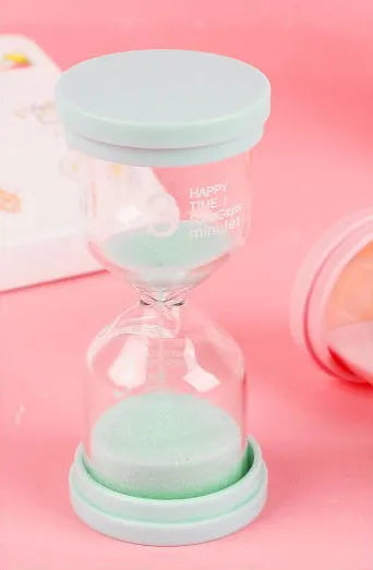 Handcrafted glass sand clock timer on a desk, showing blue sand, with modern simplicity design.