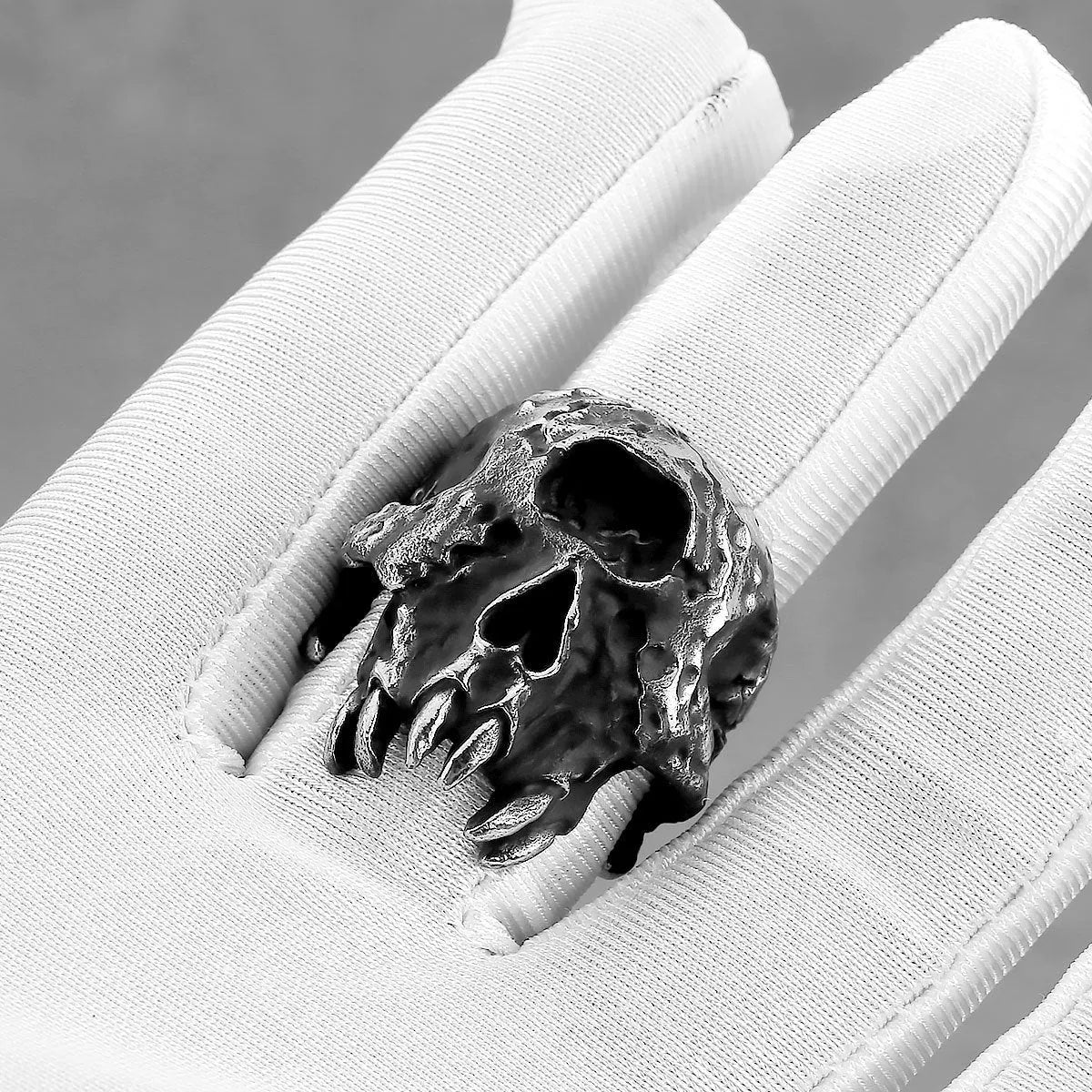 Close-up of a silver-toned alloy ring with a detailed one-eyed skull design on a black background.