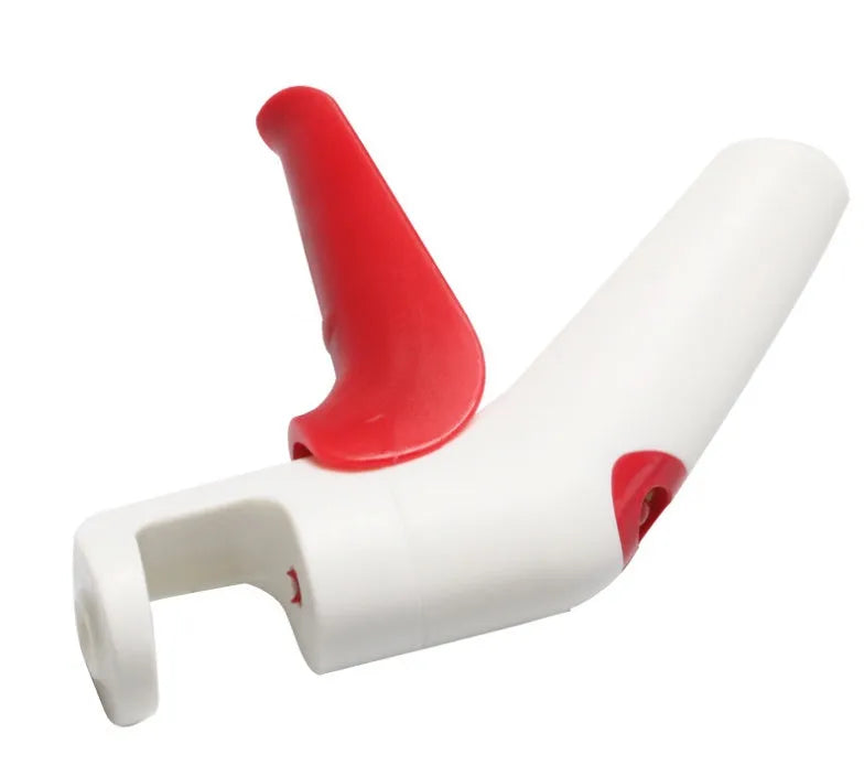 Stainless steel manual cherry pitting tool with ergonomic handle on a wooden surface.