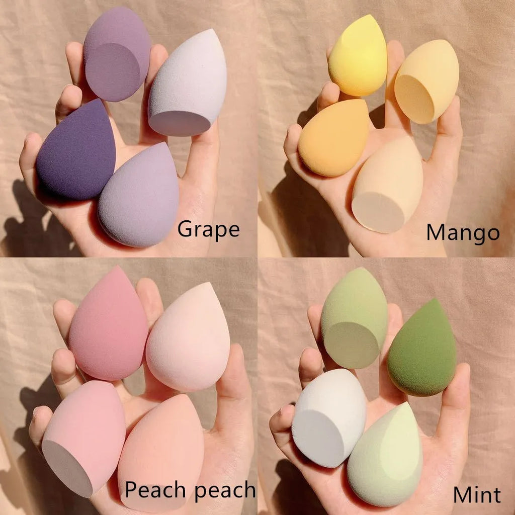Makeup egg box open showing four cube-shaped synthetic sponge beauty eggs in grape, mango, mint, and peach peach colours