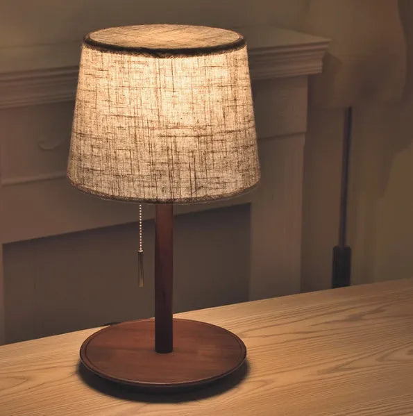 Walnut colour solid wood table lamp with a white cloth shade and a black cable switch