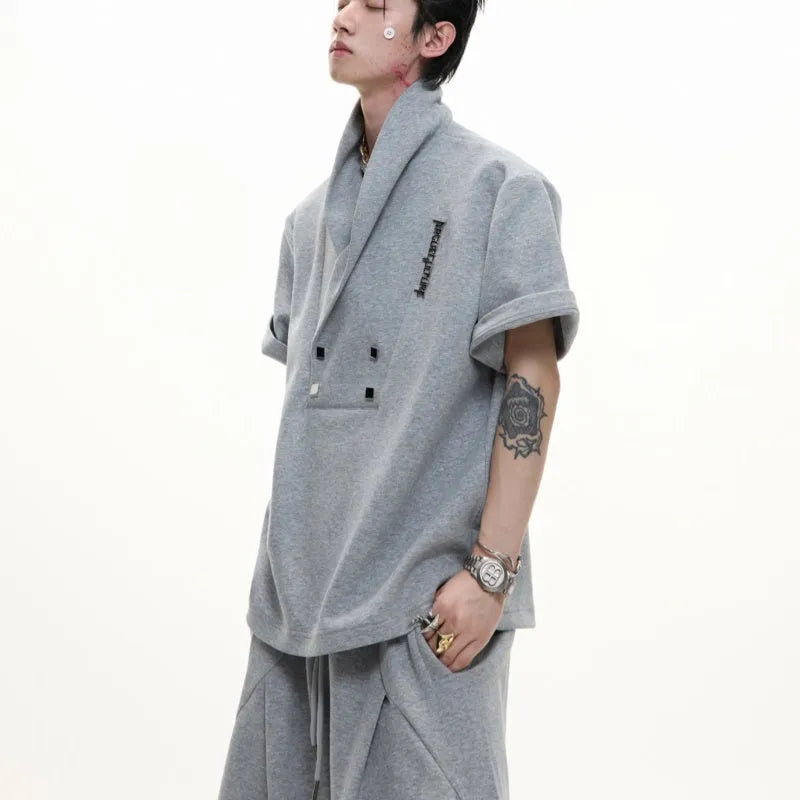 Men's dark grey V-neck cotton sports jacket with padded shoulders and metal detail, worn with matching shorts