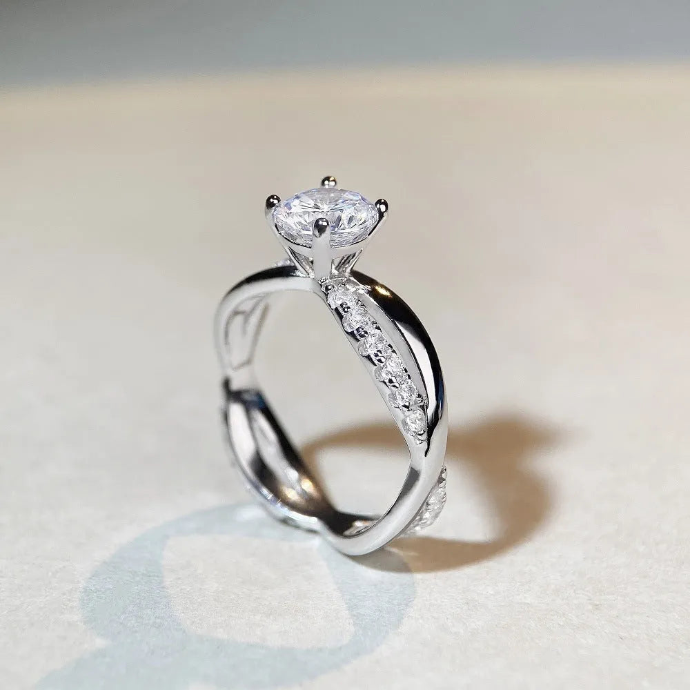 Geometric twisted silver-coloured band moissanite ring with a 1 carat stone in a four-claw setting.