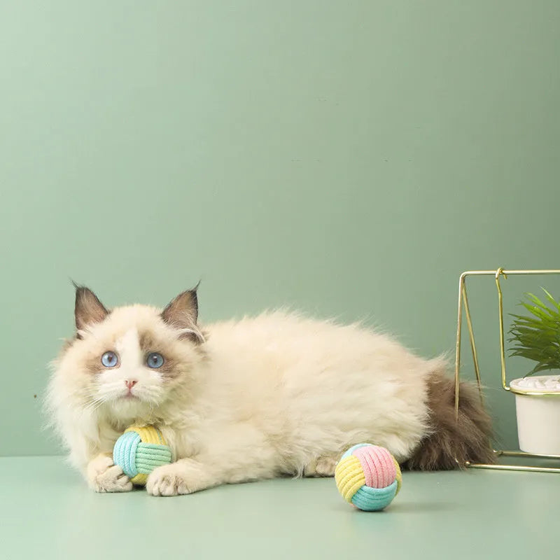 Four small handmade cotton plush balls for cats in assorted two-tone colours, shown next to a ruler for scale.