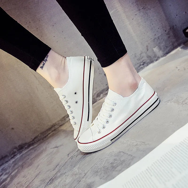 Women's solid-colour canvas shoes in black, shown on a foot from a side angle.