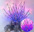 Silver branch LED tree lamp in a vase emitting warm white light, a decorative room centrepiece.