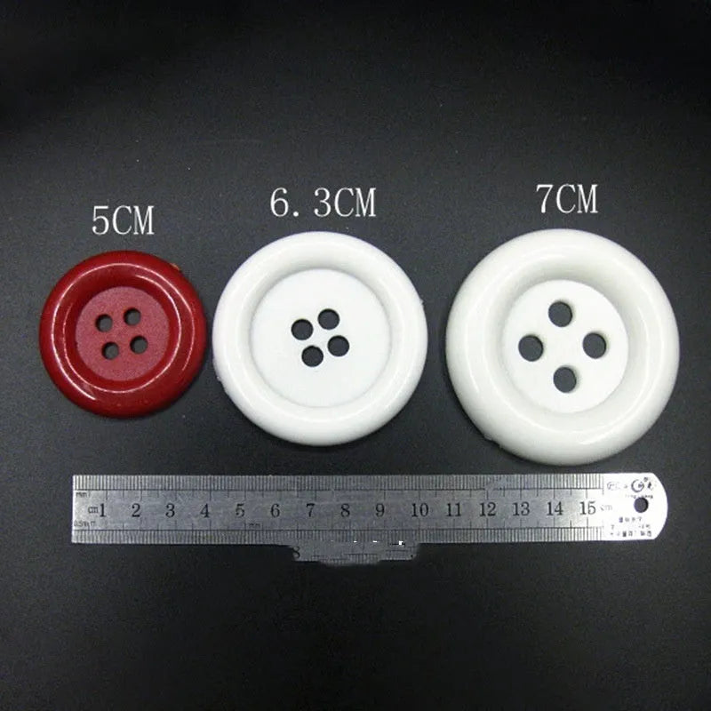 Assortment of oversized round plastic buttons with four holes in various colours and sizes on a white background.