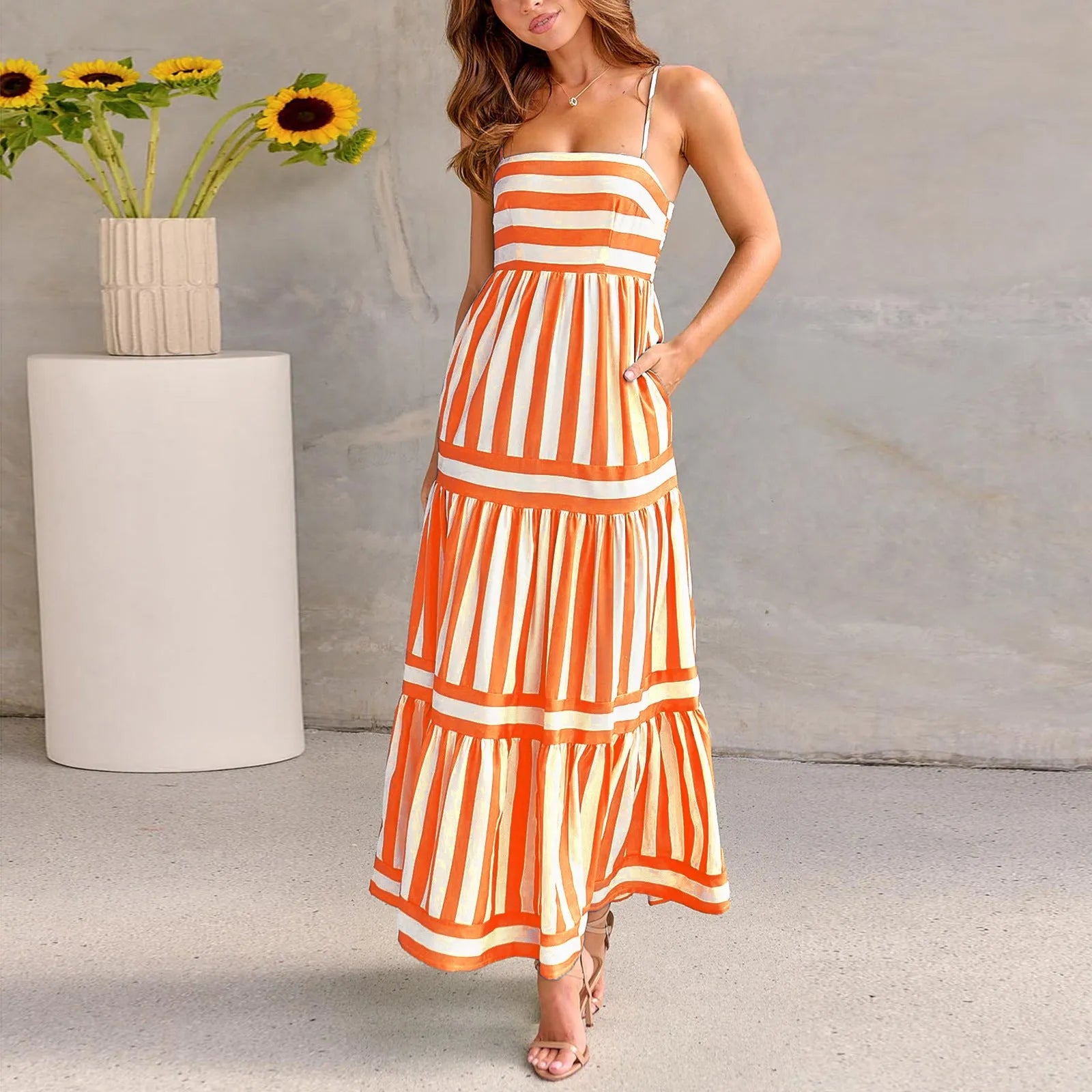 Women's long striped suspender dress with an open back and pockets on a beach