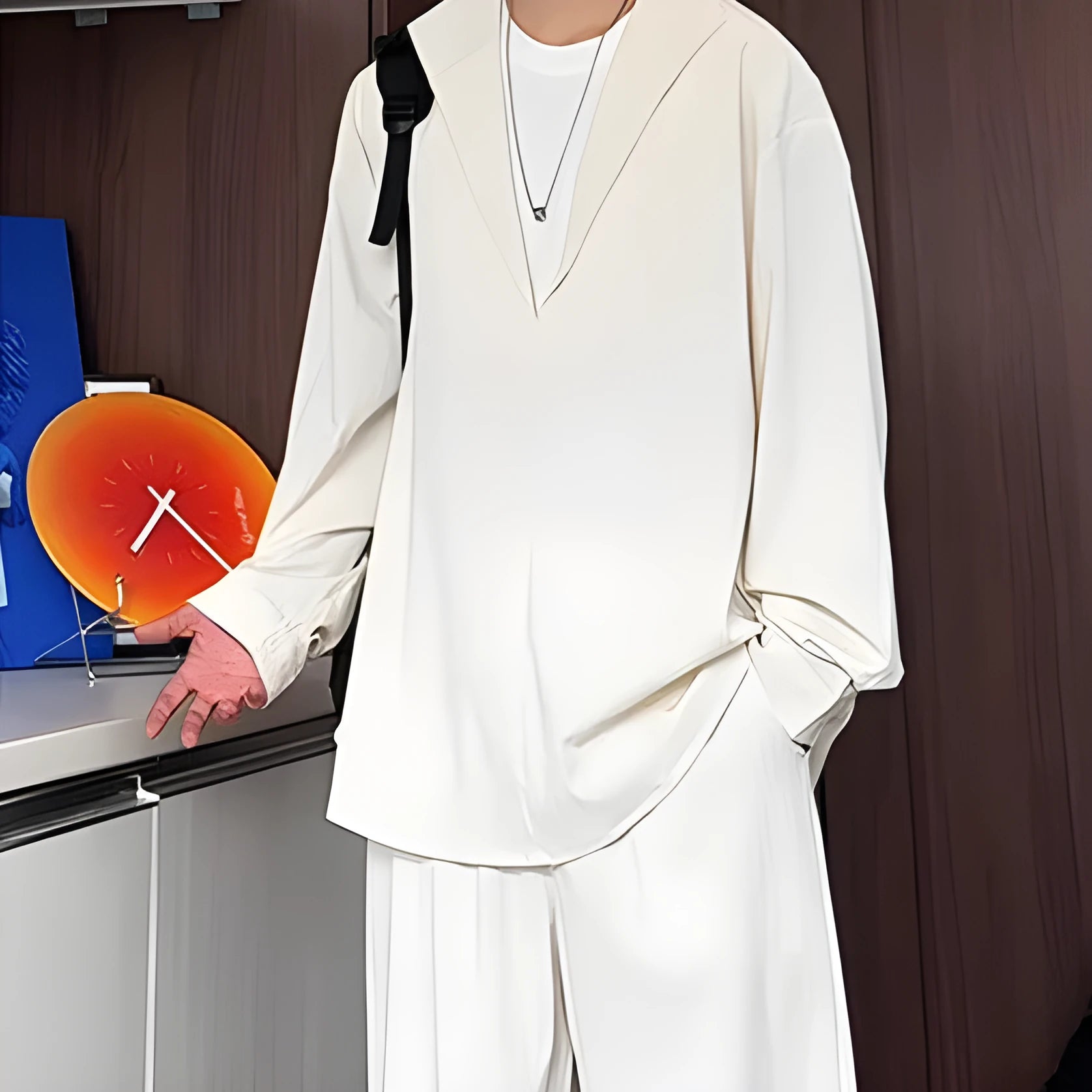 Man wearing a slim-fit apricot-coloured long sleeve polo shirt and matching trousers from a casual two-piece set.
